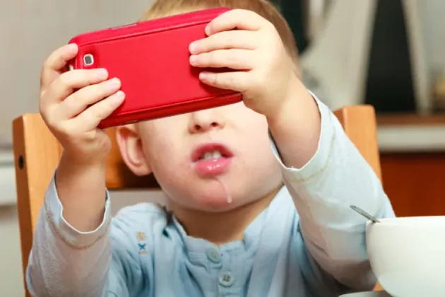 Litet barn som fotograferar med en röd mobil inomhus