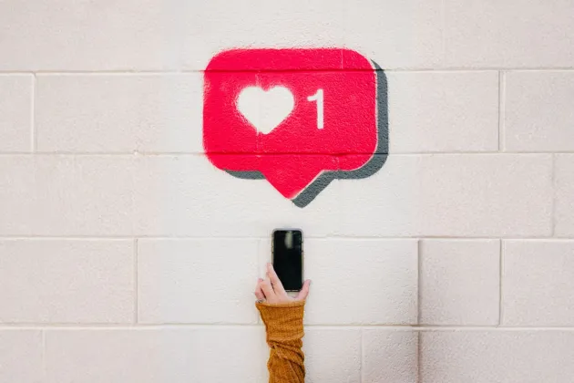 Illustrativ bild, hand håller i mobil med en gilla-markering 